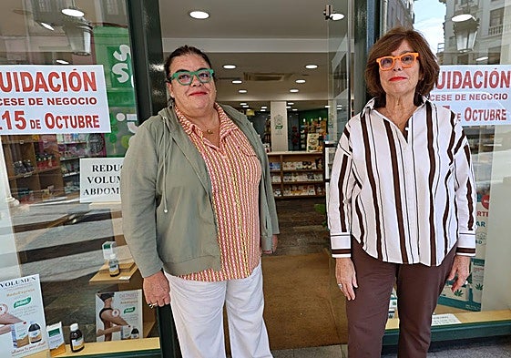 Las hermanas Eva y Elena Sastre posan delante de la puerta de su comercio de Cebadería.