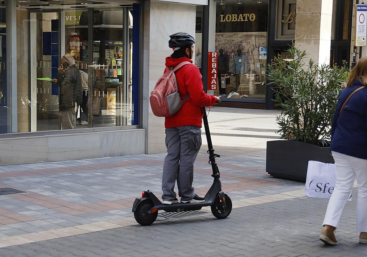 Una mujer con un patinete, en la calle La Cestilla.