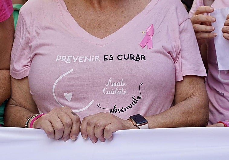 Una mujer, con camiseta y lazo para recordar la importancia del diagnóstico precoz en el cáncer de mama.