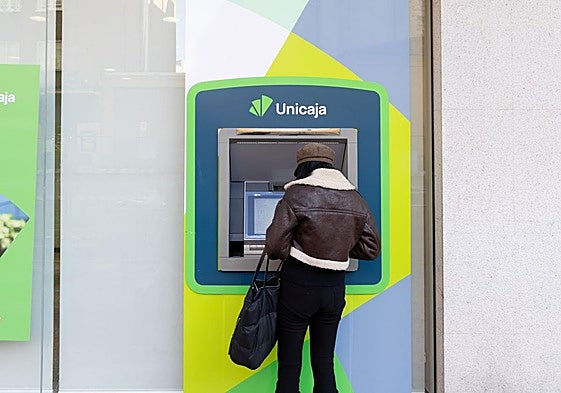 Una mujer saca dinero de un cajero, en una imagen de archivo.