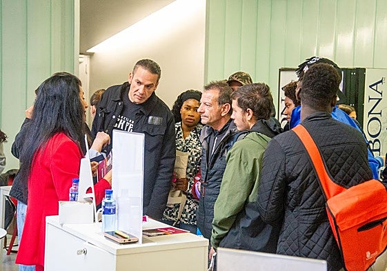 Varias personas siguen las explicaciones en el puesto de una empresa de la feria.