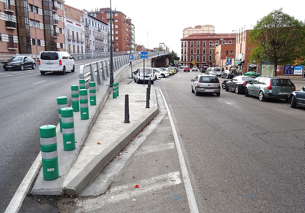 Imagen principal - Arriba, la acera de servicio que parte del inicio del tablero hacia la calle Puente Colgante. Debajo, a la izquierda, las señales que marcan la reserva para taxis y la obligación de estacionar marcha atrás. A la derecha, detalle de esta última señal.