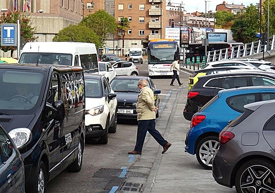 Dos peatones cruzan por la calzada entre el tráfico desde el lateral del viaducto del lado que mira a la estación de autobuses.