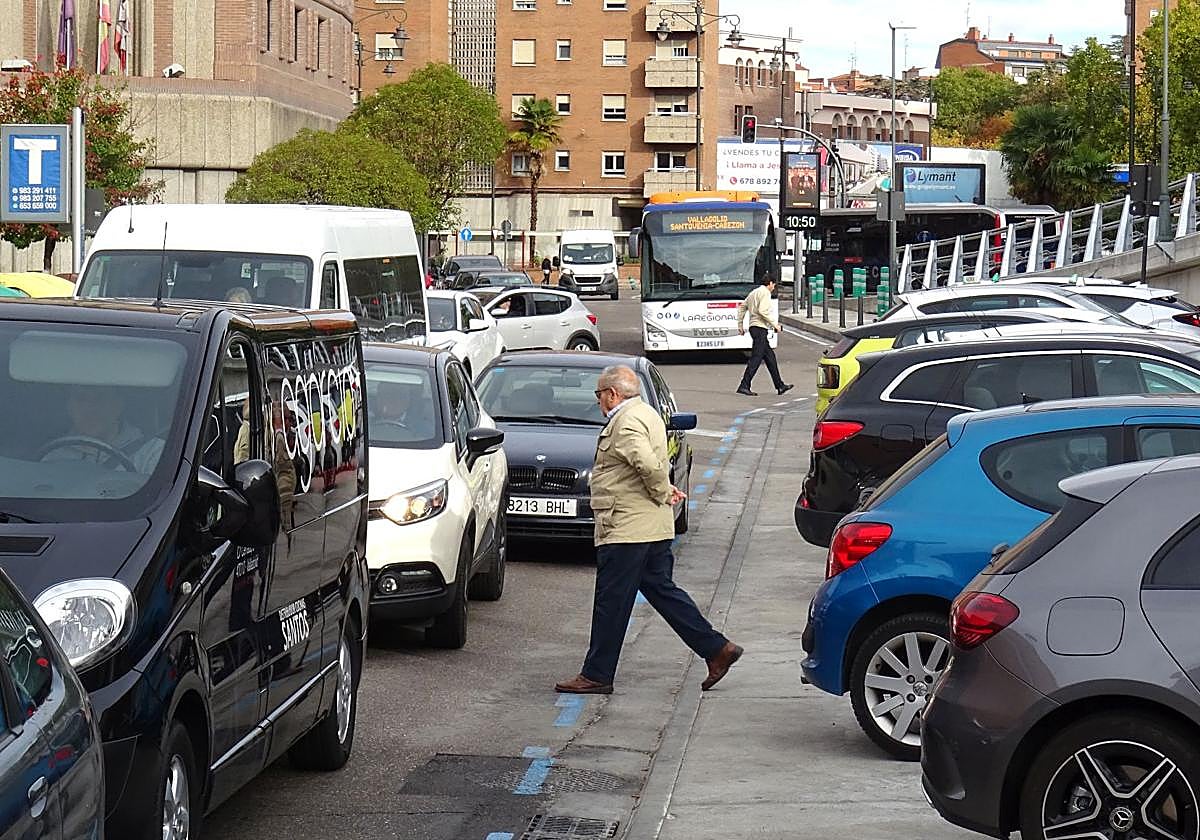 Dos peatones cruzan por la calzada entre el tráfico desde el lateral del viaducto del lado que mira a la estación de autobuses.