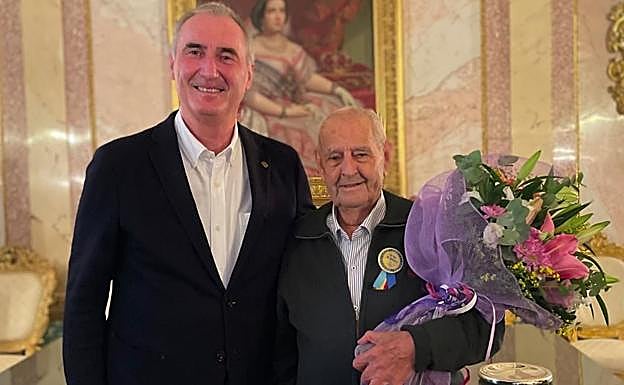 El centenario Rafael Escobar con un ramo de flores y la escarapela, junto al alcalde José Mazarías.