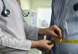 Un endocrino mide el contorno del abdomen de un paciente en la consulta.