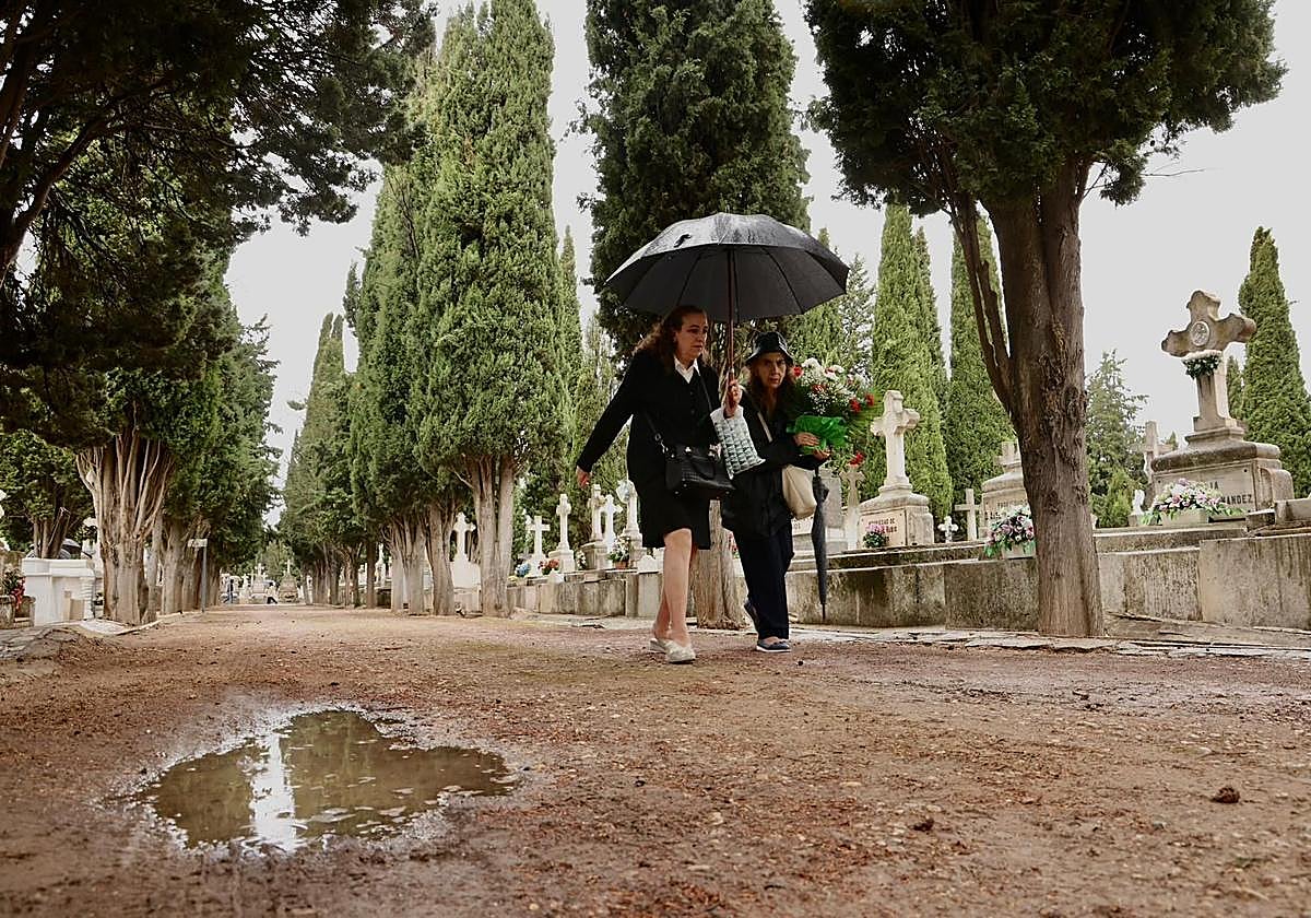 Dos mujeres llevan flores a una tumba del cementerio de El Carmen.