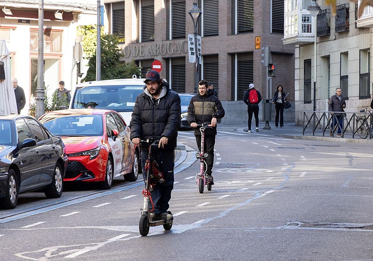 Dos usuarios de patinete eléctrico circulan por la calle Angustias.