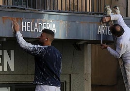 Dos personas trabajan en la reforma de un local comercial.