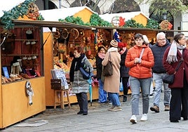 Varias personas caminan por el mercado de Navidad en la Plaza Mayor de Segovia.