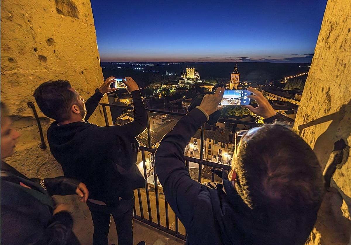 Turistas sacan fotos en una visita nocturna a la torre de la Catedral de Segovia.