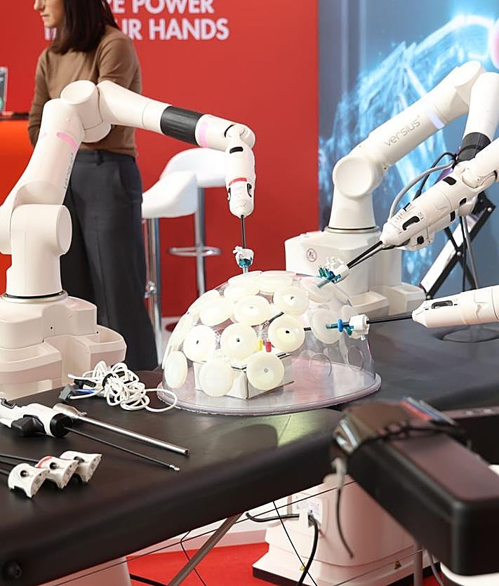 Imagen secundaria 2 - Una asistente observa el Da Vinci 5. La torre y los cuatro brazos de esta plataforma actualizada y otro de los robots, con cuatro brazos que trabajan por separado de la firma CMR, que pueden ver los cirujanos en la reunión nacional de Valladolid y que utilizan ya profesionales del Ramón y Cajal y Bellvitge.