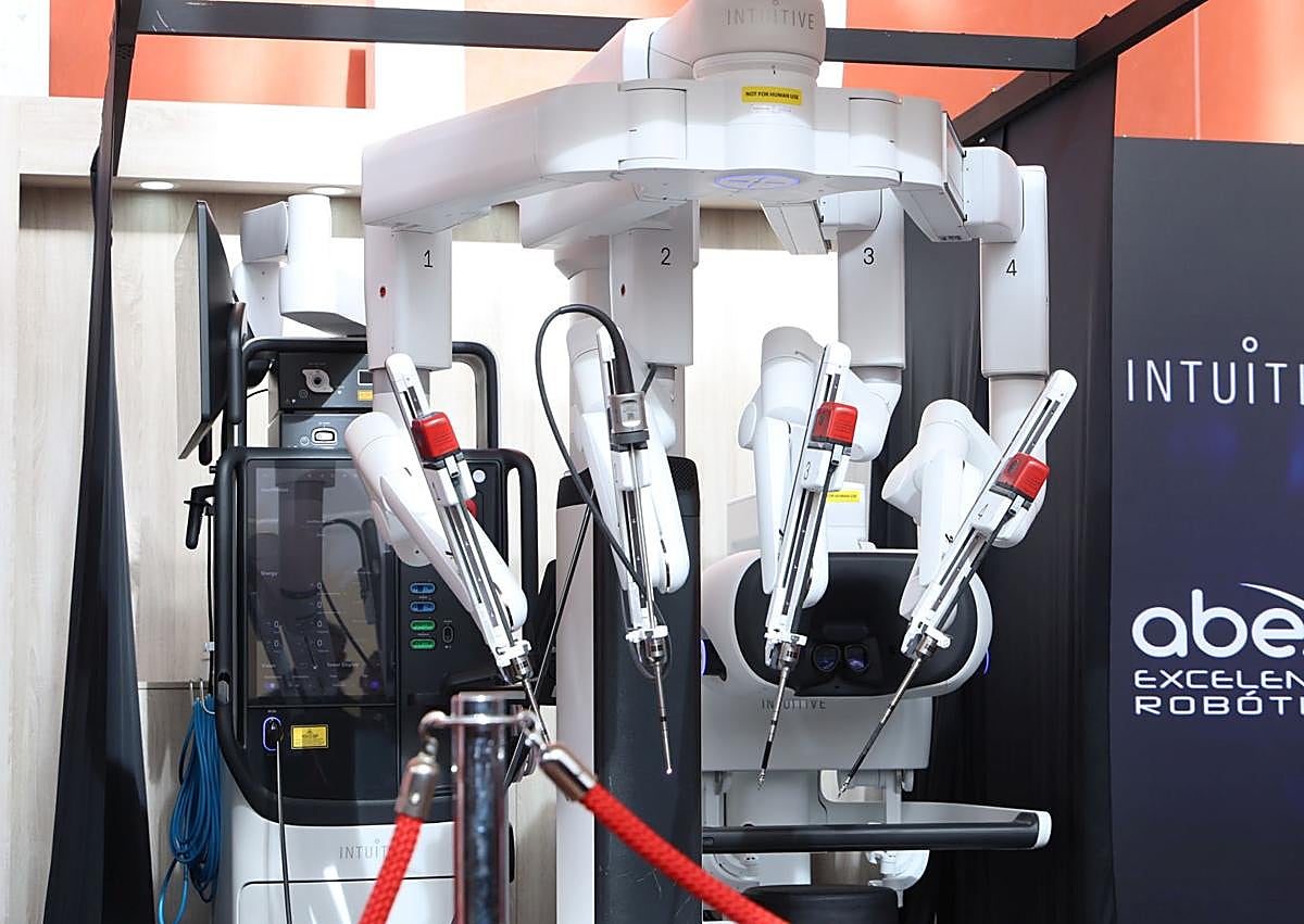 Imagen secundaria 1 - Una asistente observa el Da Vinci 5. La torre y los cuatro brazos de esta plataforma actualizada y otro de los robots, con cuatro brazos que trabajan por separado de la firma CMR, que pueden ver los cirujanos en la reunión nacional de Valladolid y que utilizan ya profesionales del Ramón y Cajal y Bellvitge.