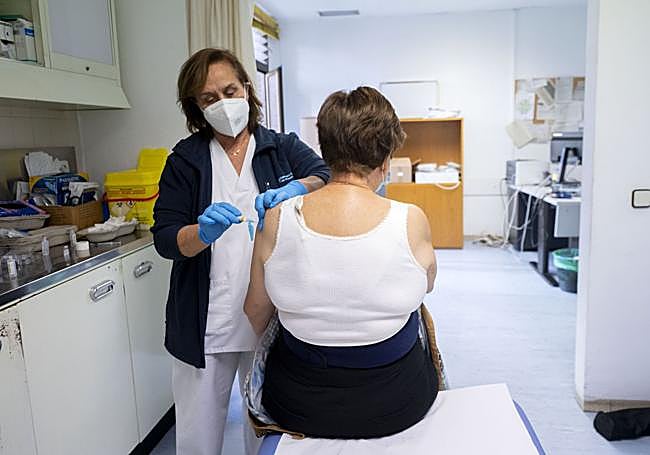 Una enfermera vacuna a una mujer frente a la gripe.