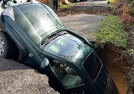 El coche de Fernando Fernández engullido por uno de los socavones que se abrieron en la carretera LE-41013 que une las localidades de La Cernada con La Faba..
