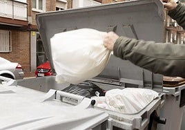 Un hombre arroja una bolsa de basura en un contenedor, en una imagen de archivo.
