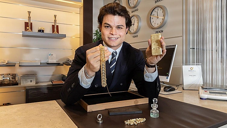 El influencer de Valladolid Isaac Sánchez, CEO de 'Tu oro vale más', sostiene una pulsera y un lingote de oro.