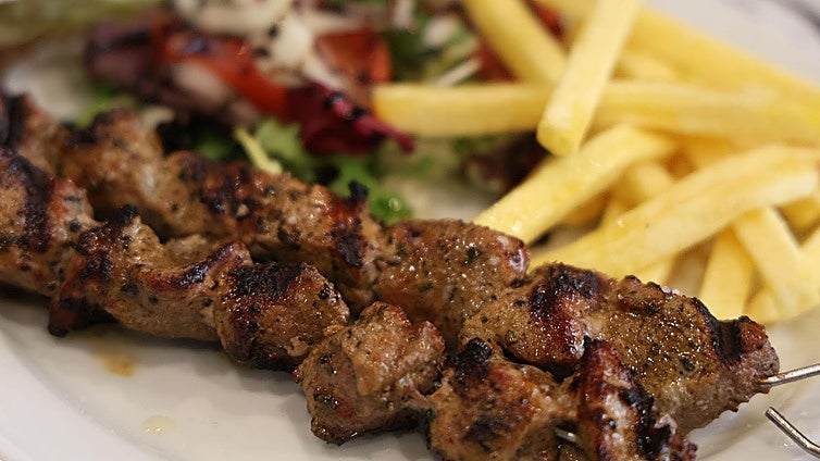 Dos pinchos morunos con patatas y ensalada.