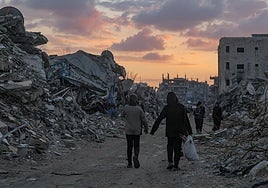Dos residentes en Gaza caminan entre los escombros.