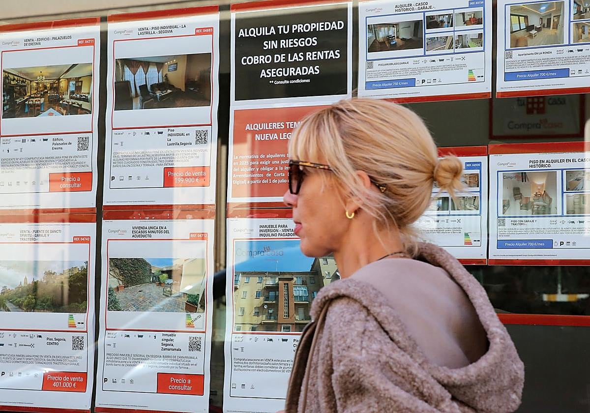 Una mujer camina por delante de una inmobiliaria en Segovia.