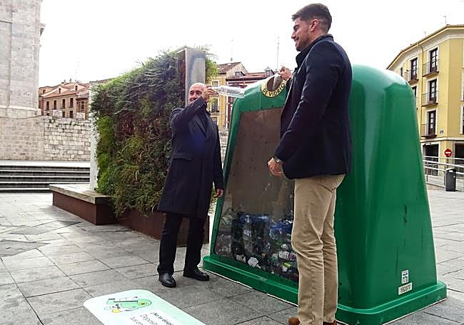 El concejal Alberto Cuadrado (izquierda) y el gerente regional de Ecovidrio, Ignacio Godín, vierten de manera simbólica dos botellas en el contenedor transparente de Portugalete.