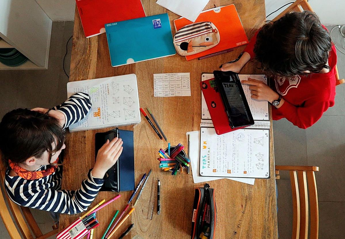 Dos escolares hacen las tareas ayudados por dispositivos digitales, en una imagen de archivo.