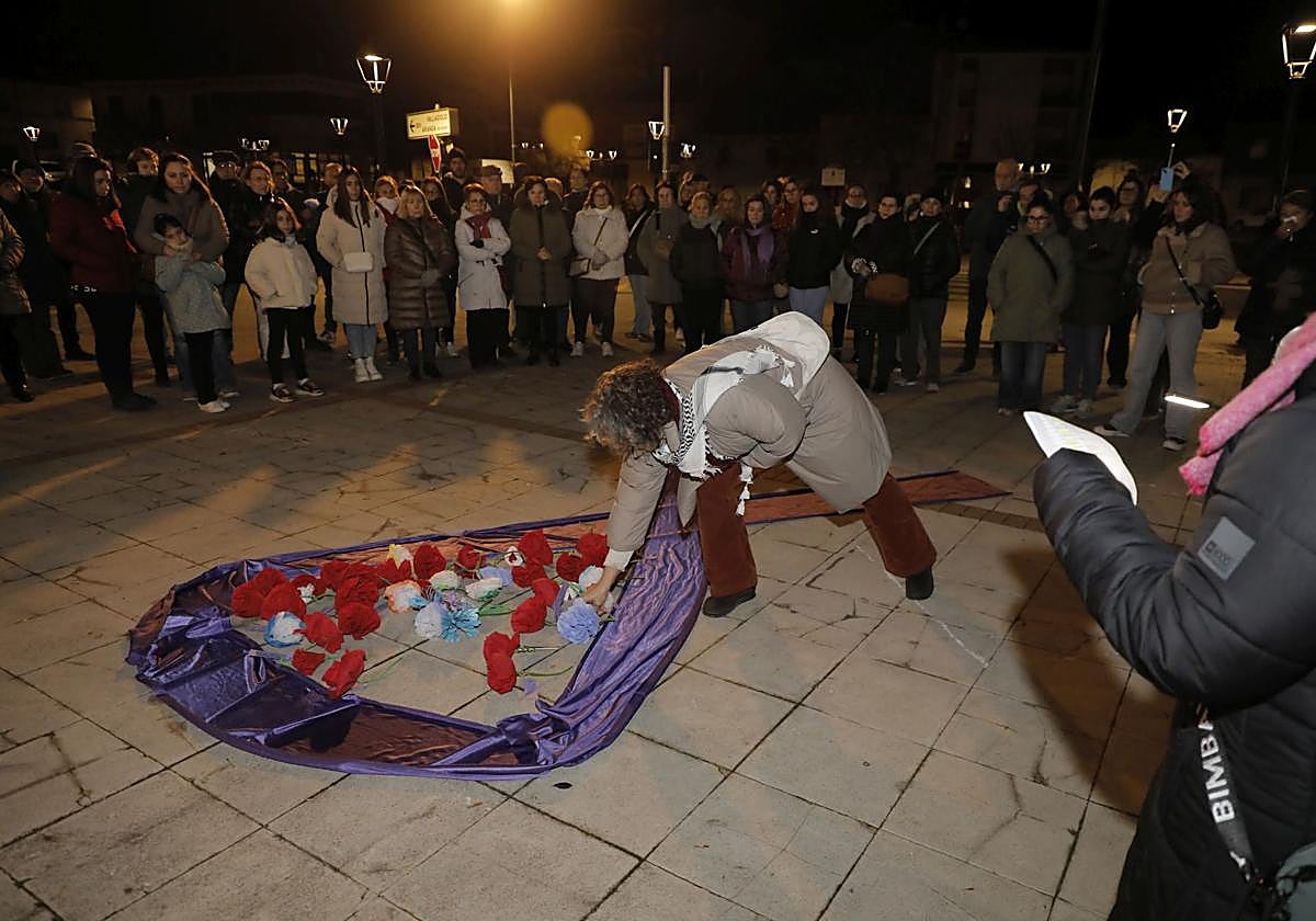 Una de las participantes en la concentración coloca una flor dentro de un lazo símbolo de esta jornada.
