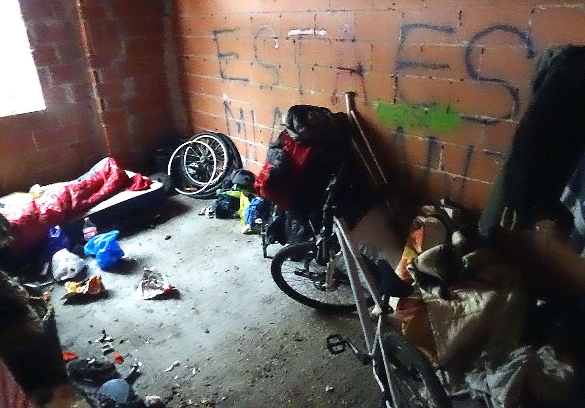 Un hombre duerme en un saco de dormir sobre un colchón y junto a su bici y su enseres en una de las estancias del abandonado residencial Rancho Grande, en el Páramo de San Isidro,