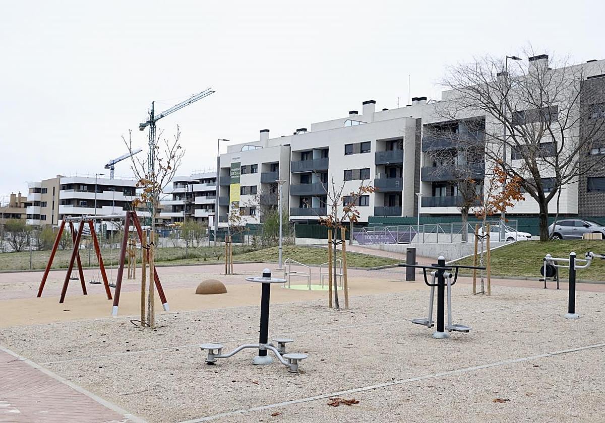 Uno de los nuevos parques inaugurados en Parquesol y, al fondo, una de las promociones en construcción en la ladera sur.