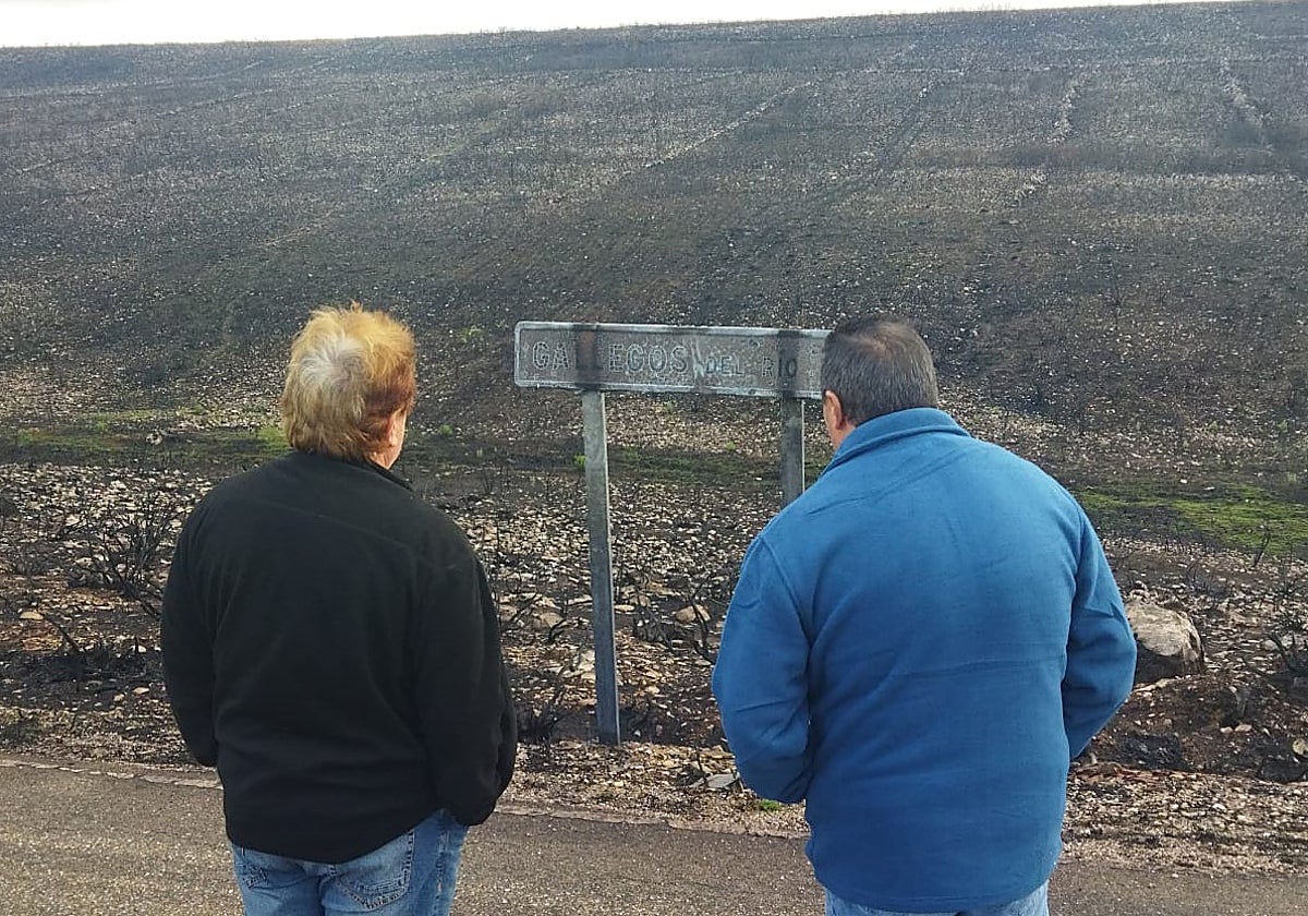 El alcalde (izqda) y un vecino de Puercas divisan el cartel quemado de Gallegos del Río.