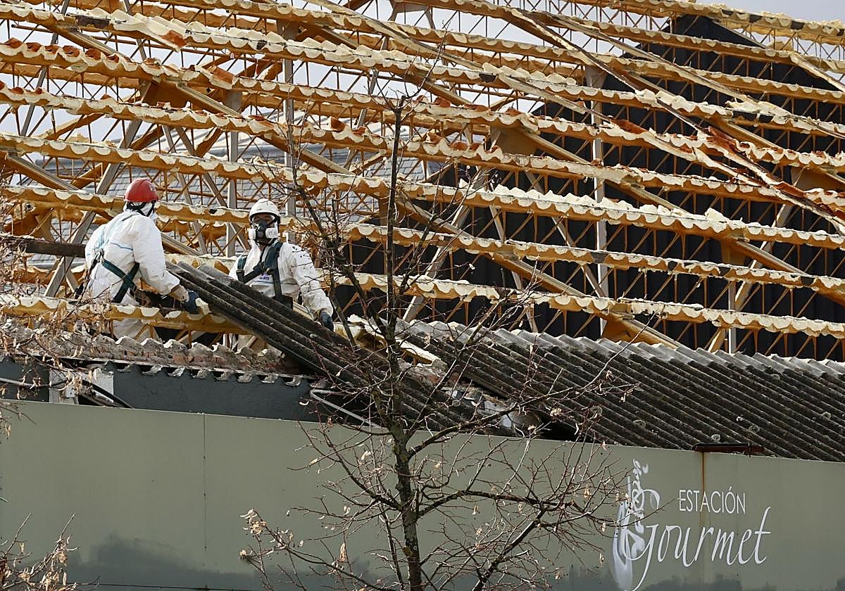 Dos operarios retiran este jueves la uralita de la cubierta del edificio de Estación Gourmet.