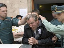 Varios agentes del cuerpo especial de intervención de la Guardia Civil introducen en un coche policial al ruso Gennadios Petrov tras pasar a disposición del juez Baltasar Garzón. /EFE