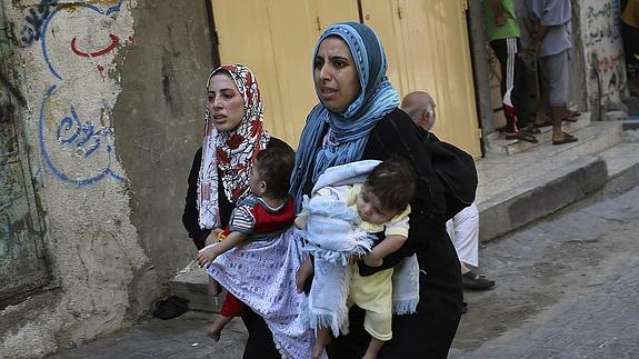 Unas mujeres palestinas con sus hijos en brazos salen de sus casas y buscan refugio