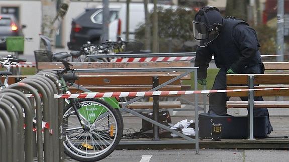 Un policía francés examina una maleta abandonada.