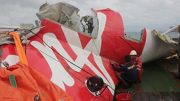 Dos operarios examinan la cola recuperada del avión. 