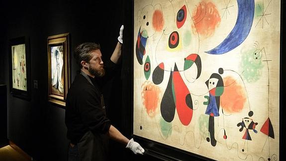 Un trabajador coloca la obra 'Mujeres, Luna, Pájaros', de Joan Miró. 