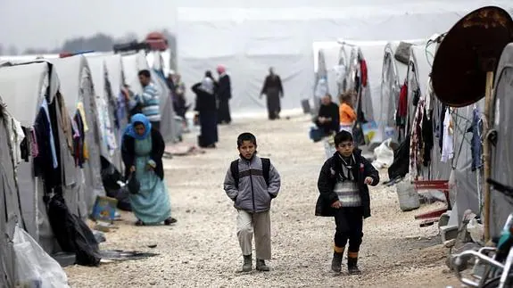 Unos niños refugiados sirios caminan entre tiendas de campaña.