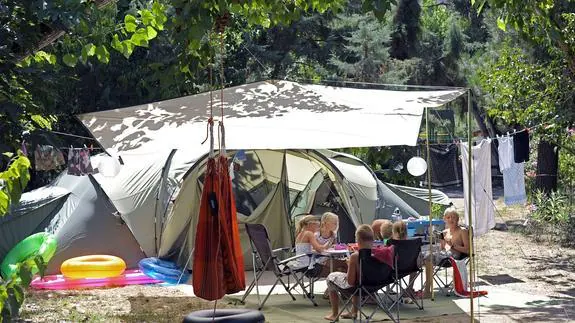 Niños juegan junto a una tienda de campaña de un camping.