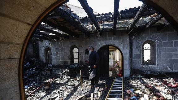 Un clérigo inspecciona los daños causados por el incendio.