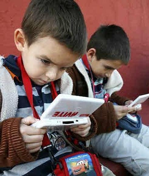 Unos niños juegan con sus consolas.