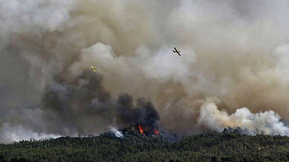 Un avión combate el fuego que avanza hacia Sant Salvador de Guardiola, cerca de la carretera C-37 que une Manresa con Igualada.