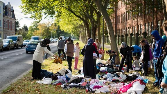 Refugiados buscan entre ropa donada frente a un centro de acogida en Berlín-Spandau, Alemania.