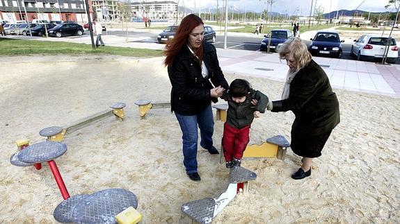Un niño juega con su madre y su abuela en un parque. 