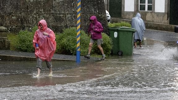 Tres peregrinos en una calle inundada en Santiago de Compostela.