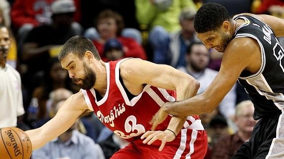 El jugador español de Grizzlies Marc Gasol (i) defiende el balón del atacante Tim Duncan (d) de Spurs.