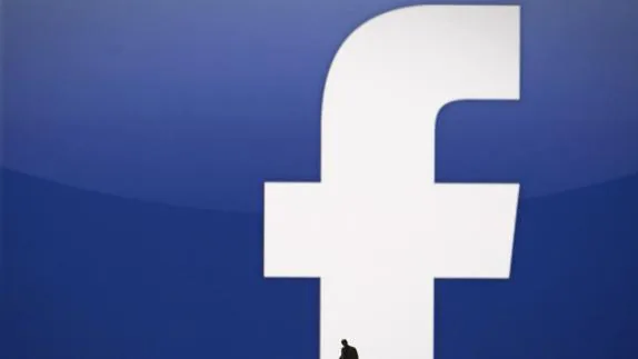 La silueta de un hombre con el logo de la red social Facebook de fondo.