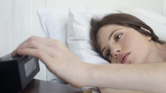 Una mujer apaga el despertador tras una noche de insomnio.