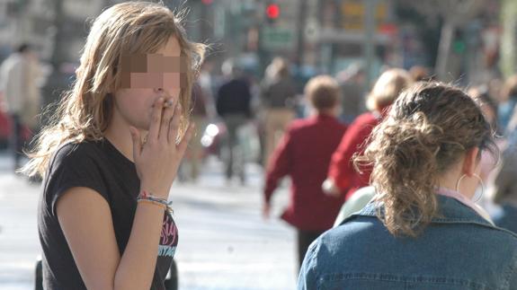 Una adolescente fuma un cigarrillo