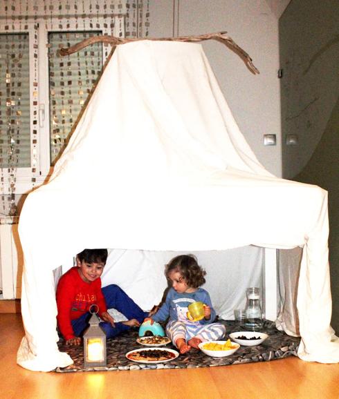 Niños disfrutan de un pícnic bajo la mesa del comedor. 