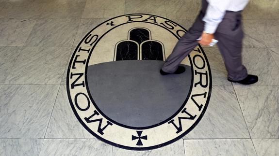 Un hombre camina sobre el logo del Monte dei Paschi en sus oficinas de Roma.